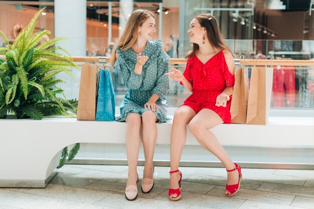 Amigos de tiro largo hablando en el centro comercial