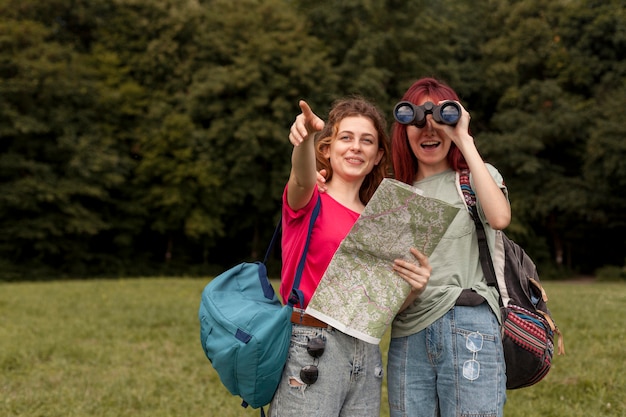 Foto gratuita amigos de tiro medio con binoculares y mapa en la naturaleza