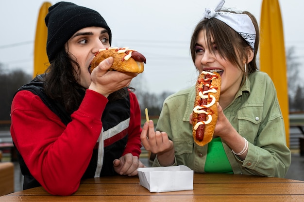 Amigos de tiro medio comiendo comida rápida de una manera divertida