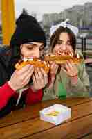 Foto gratuita amigos de tiro medio comiendo comida rápida de una manera divertida