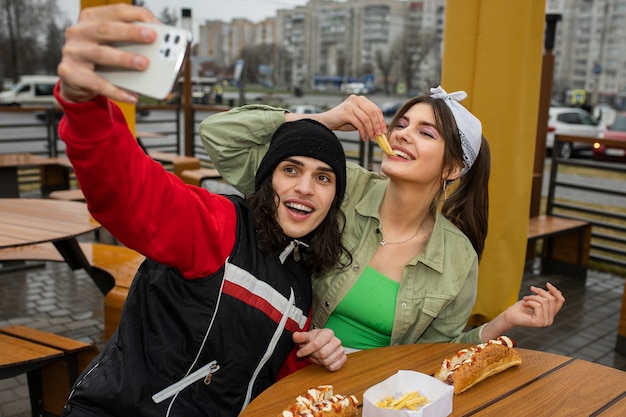 Amigos de tiro medio comiendo comida rápida de una manera divertida