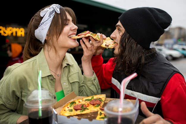 Amigos de tiro medio comiendo comida rápida de una manera divertida