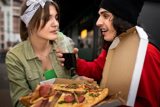 Amigos de tiro medio comiendo comida rápida de una manera divertida