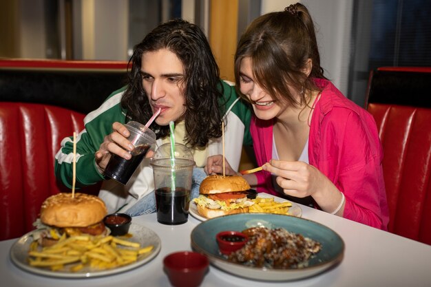 Amigos de tiro medio comiendo comida rápida de una manera divertida