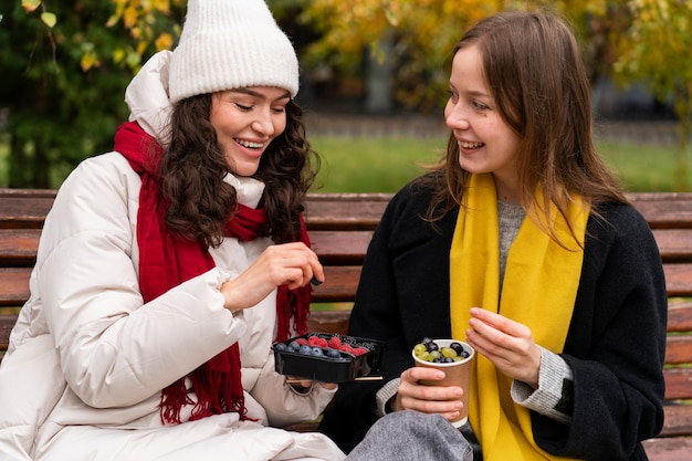 Amigos de tiro medio con deliciosas bayas en el parque.