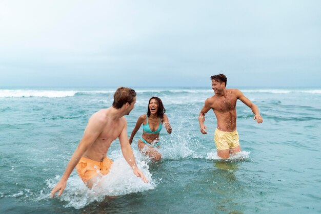 Amigos de tiro medio divirtiéndose en la playa