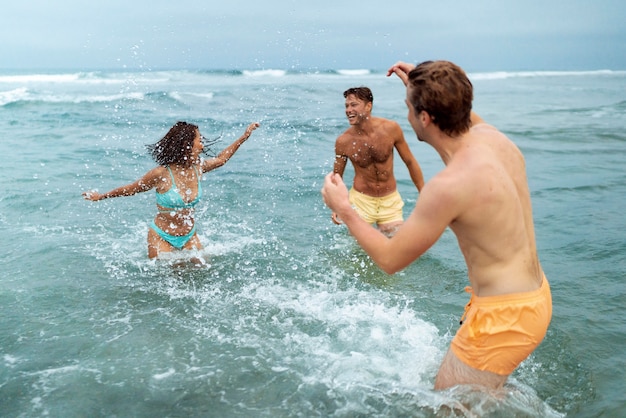 Amigos de tiro medio divirtiéndose en la playa