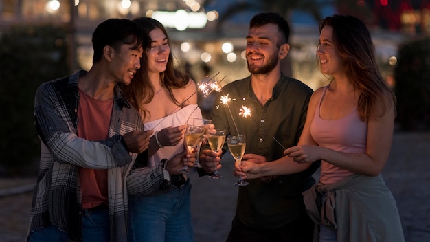 Amigos de tiro medio con fuegos artificiales en la noche