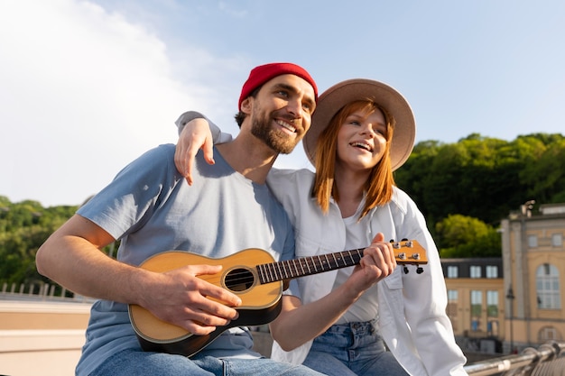 Amigos de tiro medio con guitarra pequeña