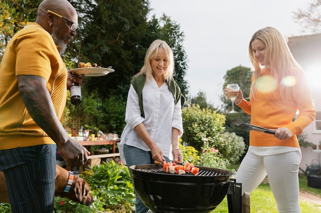 Foto gratuita amigos de tiro medio haciendo barbacoa juntos