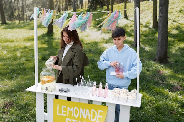 Amigos de tiro medio haciendo limonada afuera