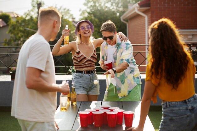 Amigos de tiro medio jugando al beer pong en la fiesta