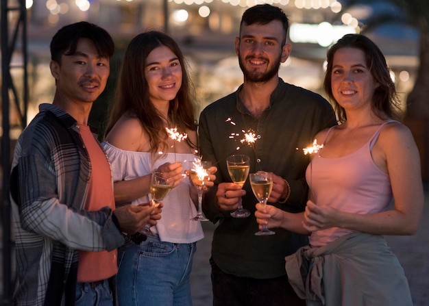 Amigos de tiro medio posando con fuegos artificiales