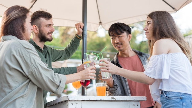 Amigos de tiro medio sosteniendo bebidas