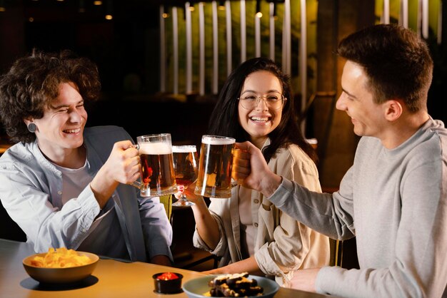 Amigos de tiro medio sosteniendo jarras de cerveza