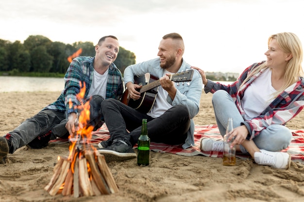 Amigos tocando la guitarra y cantando en la playa