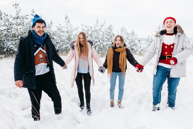 Amigos tomados de la mano en el bosque de invierno