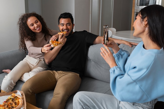 Amigos tomando fotos mientras comen pizza en casa