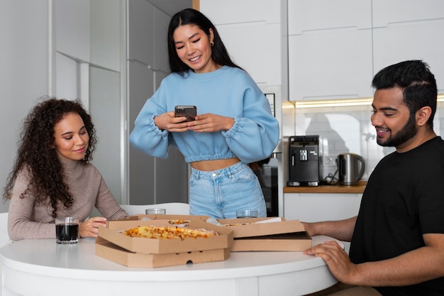 Amigos tomando fotos mientras comen pizza en casa