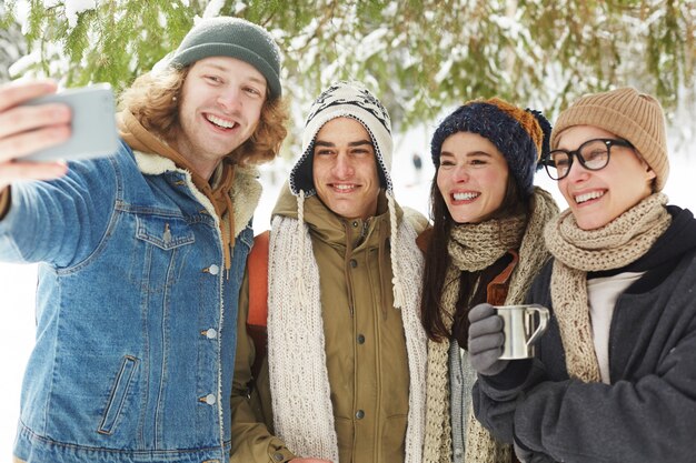 Amigos tomando Selfie en bosque de invierno