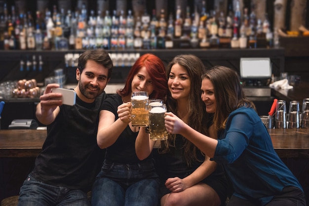 Amigos tomando un selfie en el mostrador de bar mediante teléfono móvil