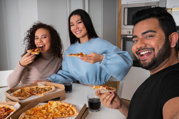 Amigos tomándose un selfie juntos mientras comen pizza