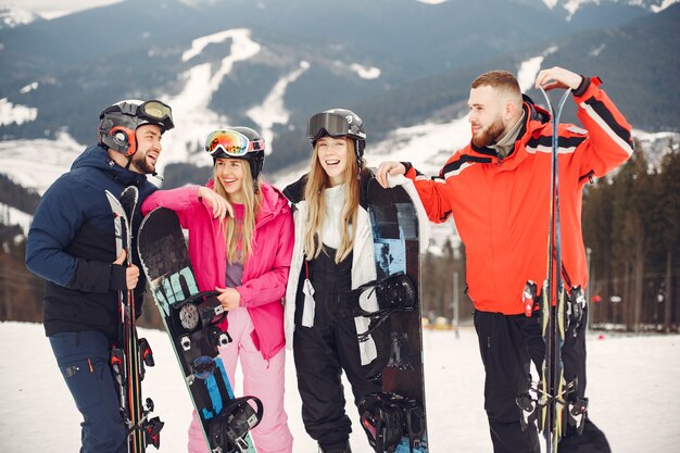 Amigos en trajes de snowboard. Deportistas en una montaña con una tabla de snowboard. Personas con esquís en las manos en el horizonte. Concepto de deportes