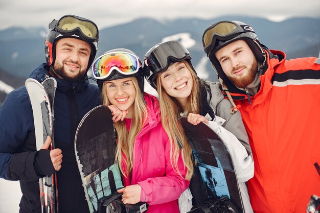 Amigos en trajes de snowboard. Deportistas en una montaña con una tabla de snowboard. Personas con esquís en las manos en el horizonte. Concepto de deportes