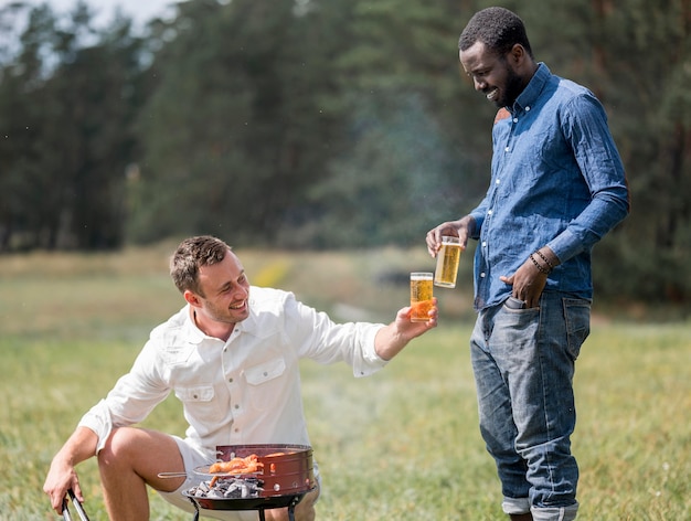 Foto gratuita amigos varones asistiendo a la barbacoa al aire libre