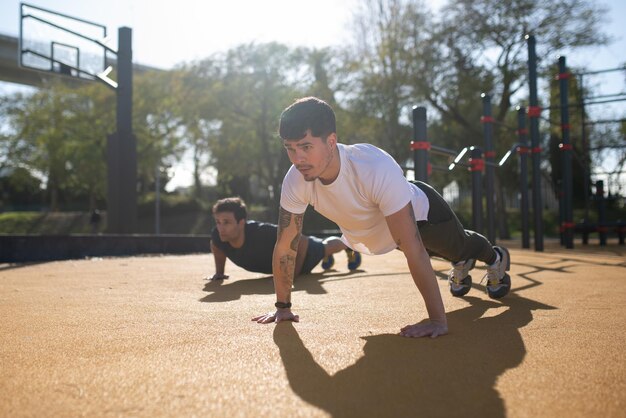 Amigos varones concentrados trabajando en un día soleado. Dos hombres con ropa deportiva en un campo de deportes al aire libre. Deporte, salud, concepto de hobby.