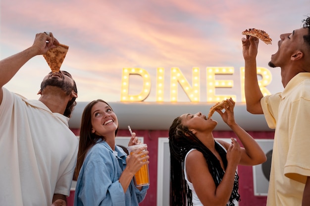 Foto gratuita amigos de vista lateral con comida al aire libre.