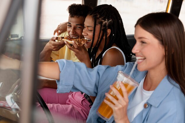 Amigos de vista lateral con comida en coche.