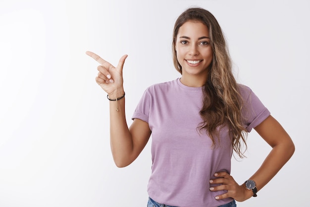 Foto gratuita amistosa niña sonriente apuntando con el dedo hacia el lado