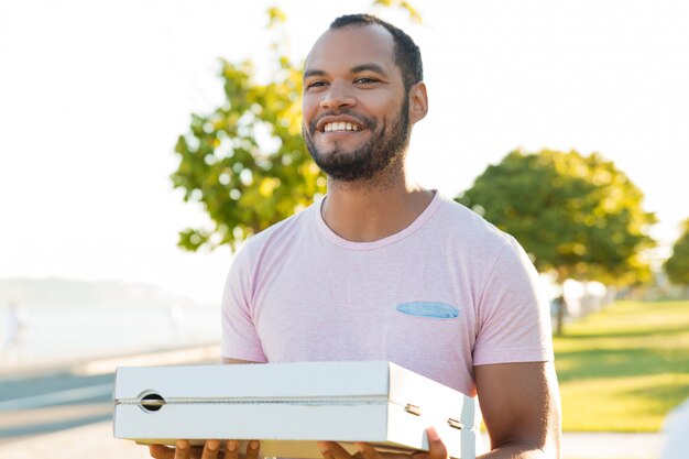 Amistoso emocionado chico guapo repartiendo pizza