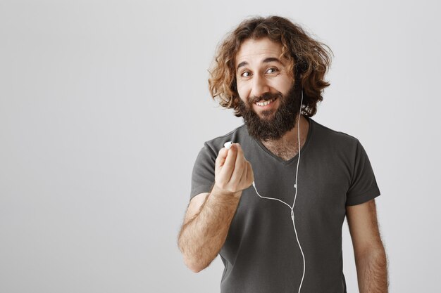 Amistoso y sonriente chico del Medio Oriente sugiere auriculares para escuchar música juntos