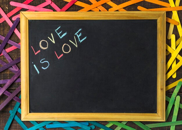 El amor es palabras de amor en la pizarra entre palos en colores LGBT