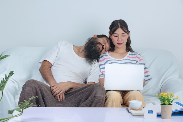 Amor de pareja están trabajando juntos mientras el viejo está durmiendo la siesta cerca de la niña en el sofá en casa.