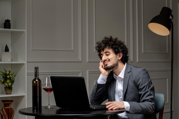 Amor virtual chico lindo guapo en traje con vino en una fecha de computadora a distancia coqueteando sonriendo