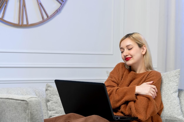 Amor virtual linda jovencita rubia en suéter acogedor en fecha de distancia de computadora abrazándose a sí misma
