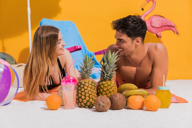 Amores jovenes lindos que mienten con la fruta en la playa en estudio