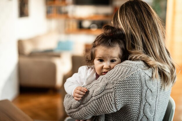 Amorosa madre abrazando a su pequeña hija en casa Centrarse en la hija