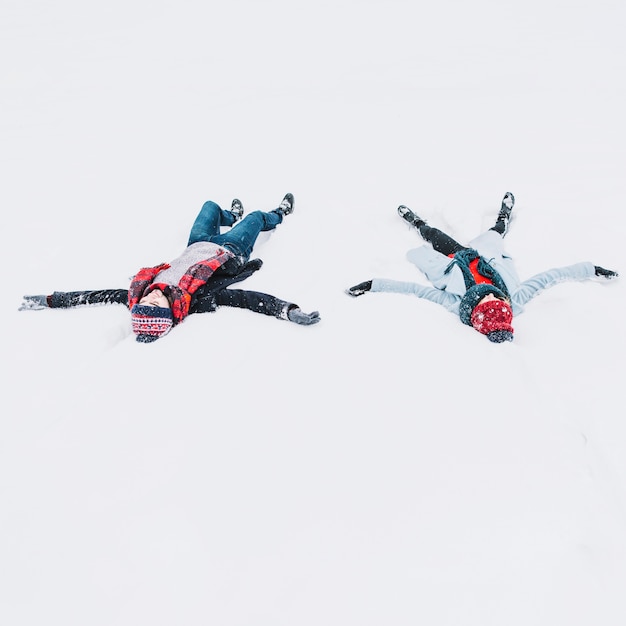 Amorosa pareja acostada en la nieve divirtiéndose