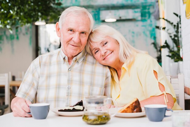 Amorosa pareja de ancianos bebiendo té y comiendo pastel