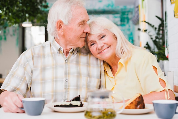 Foto gratuita amorosa pareja de ancianos bebiendo té con pastel