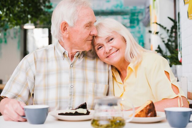 Amorosa pareja de ancianos bebiendo té con pastel