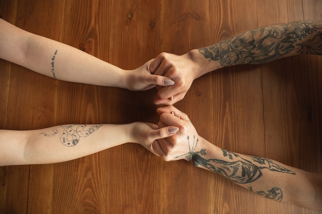 Foto gratuita amorosa pareja caucásica cogidos de la mano de cerca sobre fondo de madera. romántico, amor, relación, cariño tierno