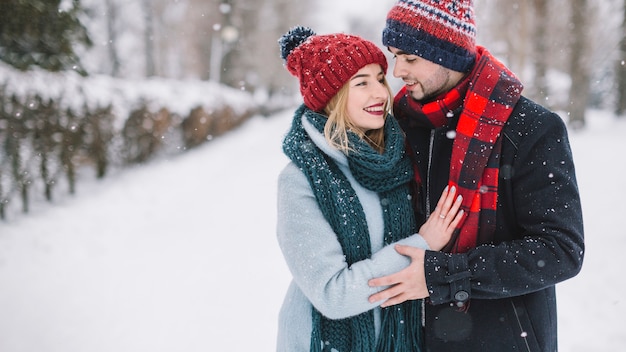 Amorosa pareja elegante en copos de nieve cayendo