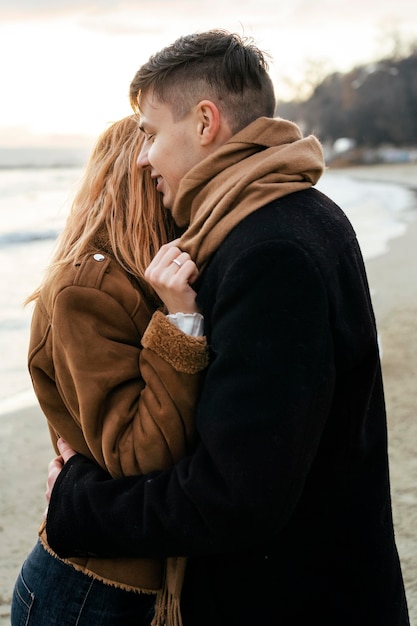 Amorosa pareja joven abrazándose en la playa en invierno