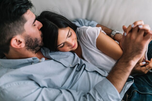 Amorosa pareja joven sosteniendo la mano del otro durmiendo