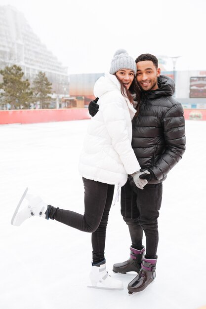 Amorosa pareja patinando en la pista de hielo al aire libre.
